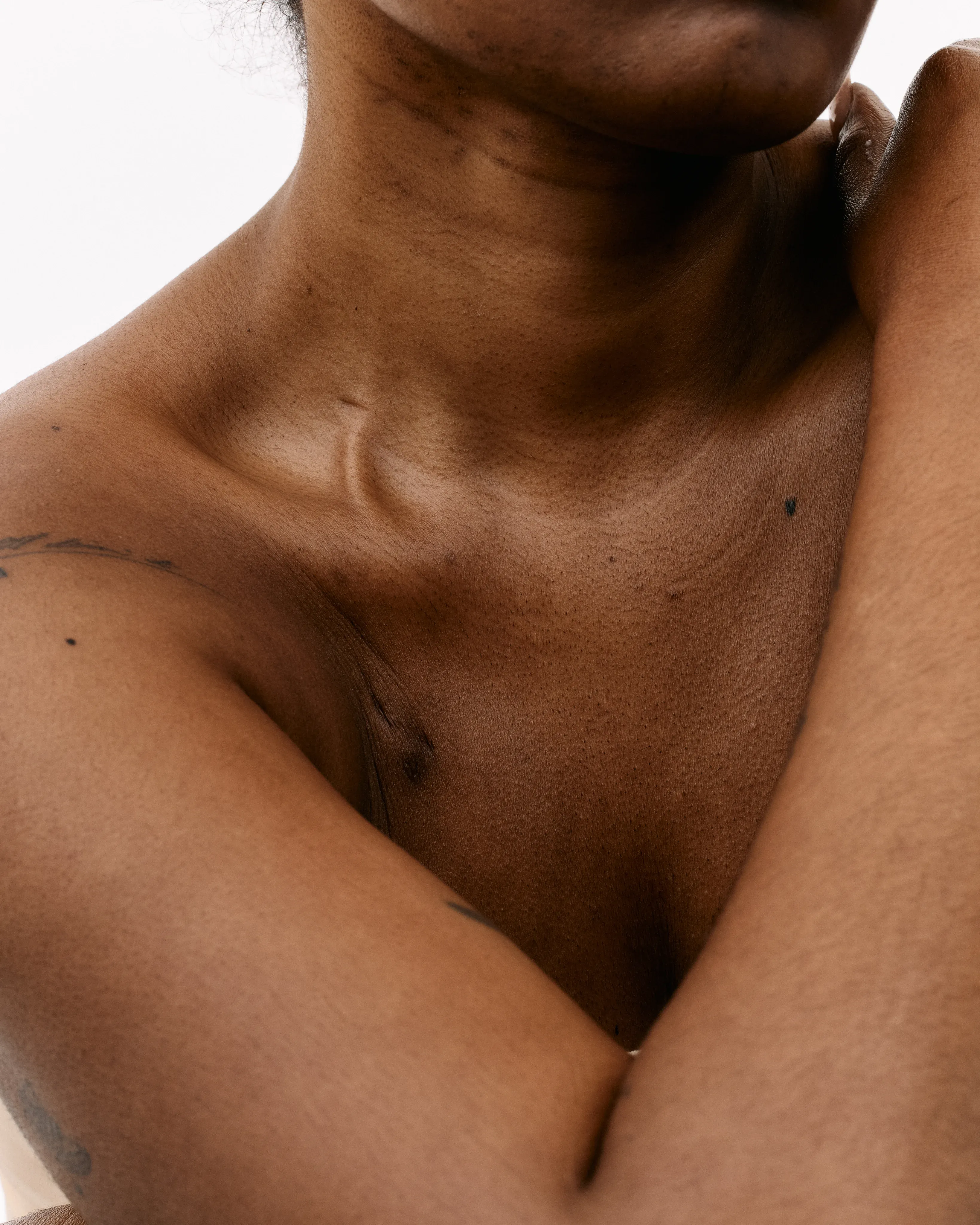 Extreme close-up of a person's collarbone and décolletage in warm, soft studio light