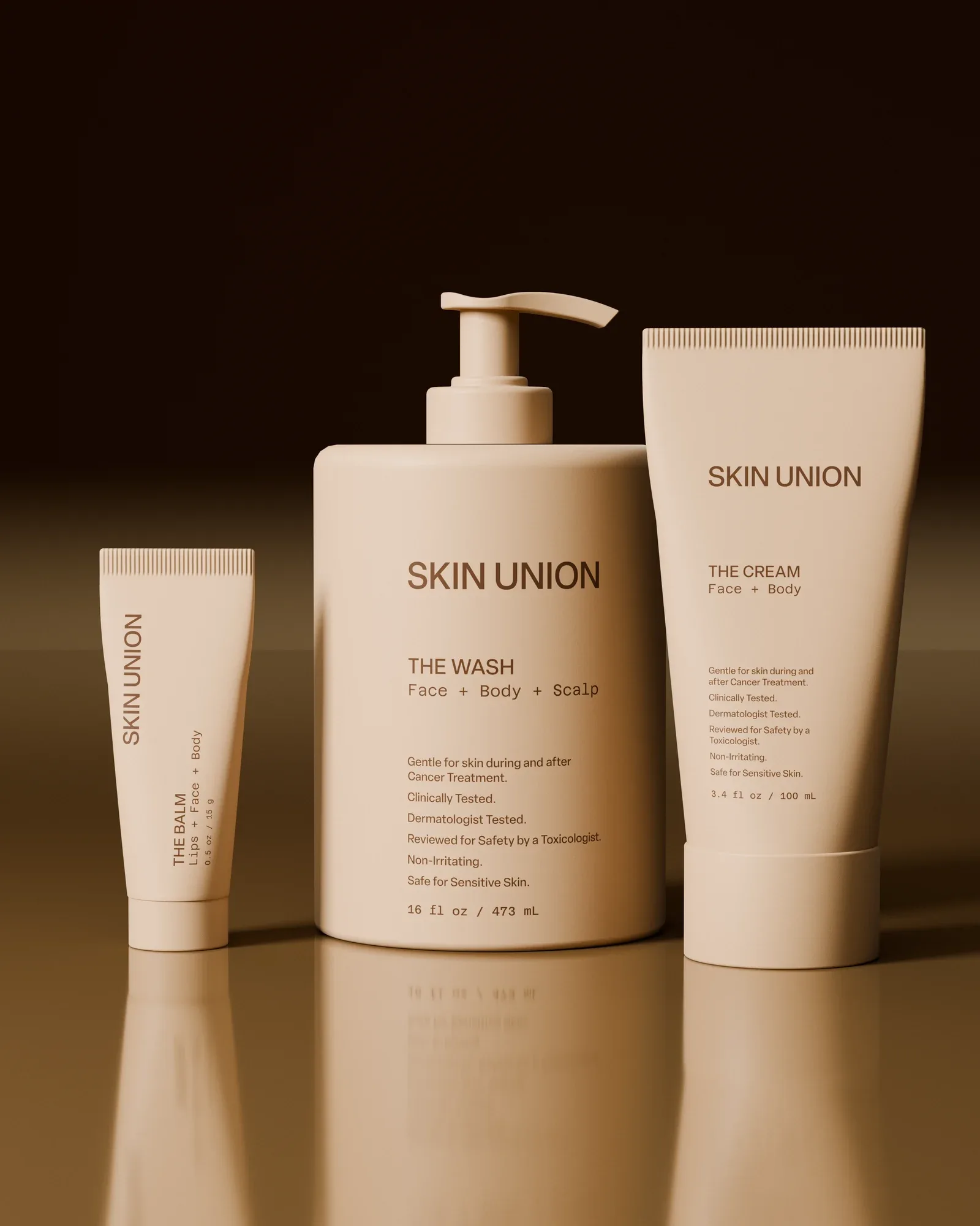 The Balm, The Wash and The Cream standing upright side by side on a reflective surface against a dark brown ground